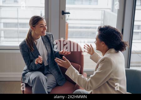 Smiling diverse businesswomen is distracted from work and talking in office during break Stock Photo