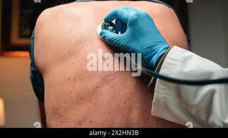 Doctor Using Stethoscope In The Back Of A Patient For Lung Check Stock Photo