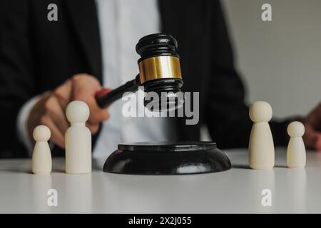 Figures of family are separated by judge's gavel. Family law, divorce lawyer and alimony concept. Stock Photo