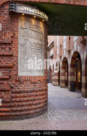 Illuminated sign Boettcherstrasse, sign embedded in the house wall to the artist Paula Modersohn-Becker and brick houses with arcades in the Stock Photo