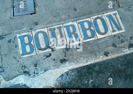 A street marker is embedded in the sidewalk on Bourbon Street in the French Quarter of New Orleans Stock Photo