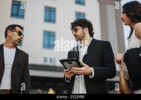 Business colleagues discussing over a tablet during an informal outdoor meeting in a city Stock Photo