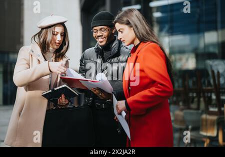 Multicultural, young, business team reviewing documents on urban street. Stock Photo