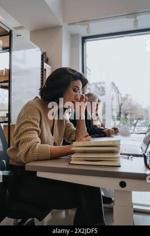 Woman working in an office, discussing business strategies and finding innovative solutions. She works on a project, using technology for success. Stock Photo