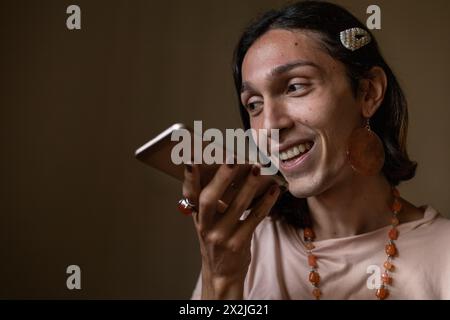 A young transgender man (22) is in his room sending a voice message from his cell phone. Concept of transgender and communication Stock Photo