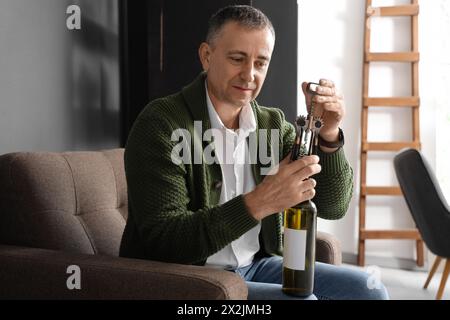 Mature man opening bottle of wine at home Stock Photo