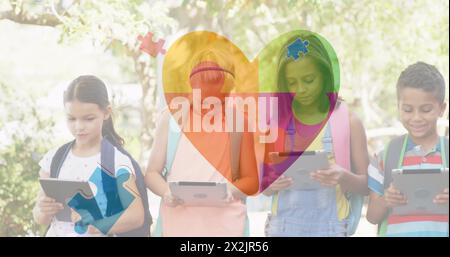 Image of colourful puzzle pieces heart over school children using tablets Stock Photo