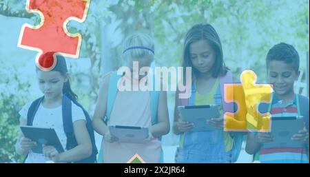 Image of colourful puzzle pieces over school children using tablets Stock Photo