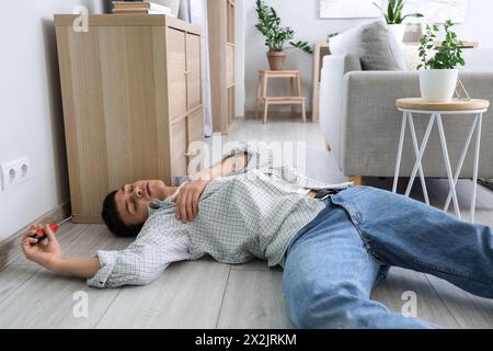 Electrocuted young man with screwdriver lying near socket at home Stock Photo