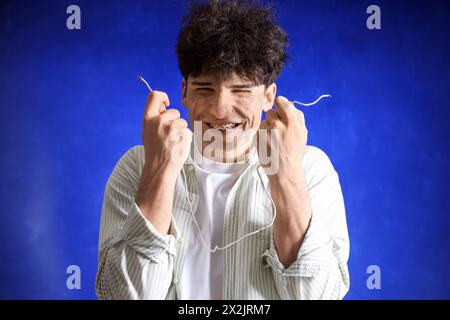 Electrocuted young man with burnt face and wire on dark background, closeup Stock Photo