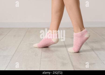 Woman in socks on laminate floor near light wall, closeup Stock Photo