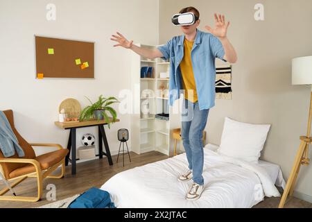 Male student using VR glasses in bedroom Stock Photo