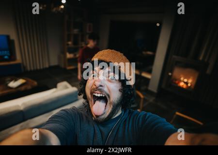 Excited man taking a selfie with a friend at a cozy home gathering Stock Photo