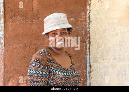 young african chubby woman with a hat holding her cellphone in the poor