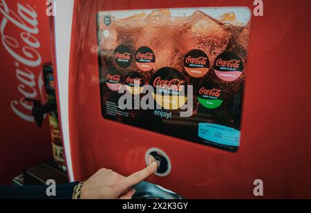 A close-up shot of a person's hand selecting a beverage from a digital Coca-Cola vending machine featuring various flavors. Ideal for illustrating mod Stock Photo