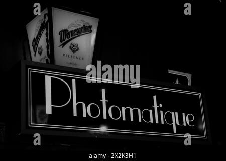 This striking black and white image showcases a neon sign labeled 'Photomatique' alongside a vintage beer advertisement for 'Dreher Beer,' capturing a Stock Photo