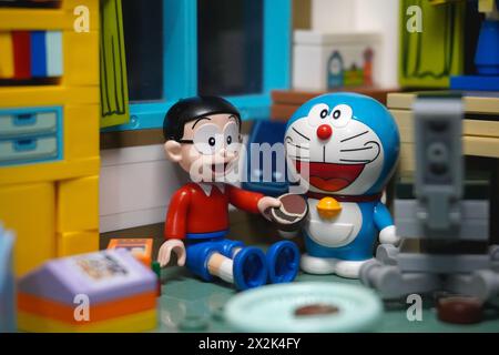 Japanese toy figures (Nobita and Doraemon) sitting and eating chocolate cake together Stock Photo