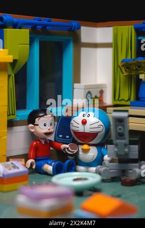 Japanese toy figures (Nobita and Doraemon) sitting and eating chocolate cake together Stock Photo