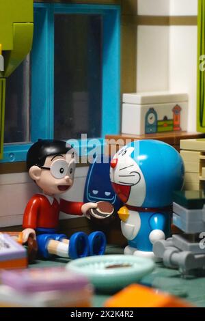 Japanese toy figures (Nobita and Doraemon) sitting and eating chocolate cake together Stock Photo