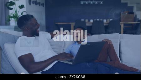 Image of data over happy african american father and son using laptop at home Stock Photo