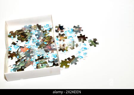 Puzzles scattered from a box lie on a white background. Stock Photo