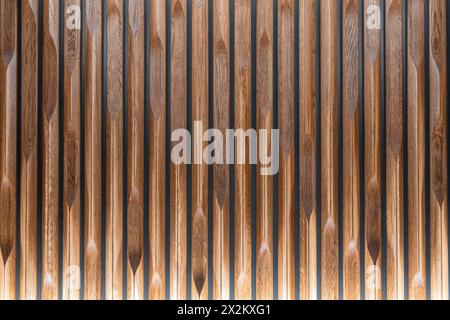 Decorative wooden panel made from solid oak of vertical grooved slats with varied edge patterns with bottom backlight as background Stock Photo