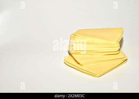On a white background, a slide of cheese sliced into thin slices. Stock Photo