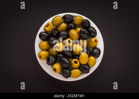 Black and green olives in a white bowl on a black background Stock Photo