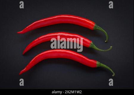 Three red chili peppers on a black background Stock Photo