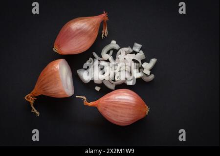 Whole, half and chopped shallots on black background Stock Photo