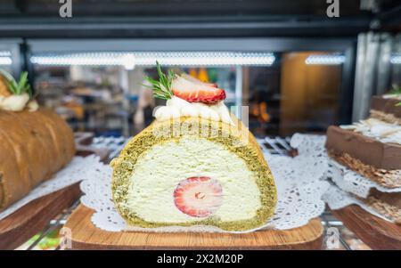 Strawberry creamy cakes on display at a café. Unrecognizable waiters in the background. Stock Photo