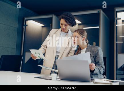 Focused female colleagues discussing project before showing presentation to team leader in office Stock Photo