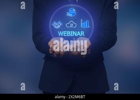 Webinar. Businessman holding virtual icons on color background, closeup Stock Photo