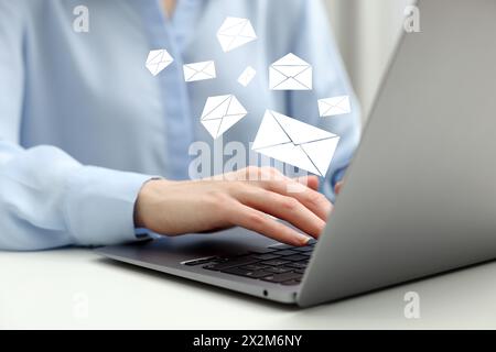 Email. Woman using laptop at table, closeup. Letter illustrations over device Stock Photo