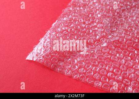 Transparent bubble wrap on red background, closeup Stock Photo