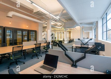 A bright and spacious office featuring an open-plan layout with ergonomic chairs, large windows, and contemporary interior design elements Stock Photo