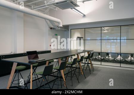 A contemporary meeting room in an office, equipped with a long table, chairs, and a laptop, showcasing a sleek and modern design, available for busine Stock Photo