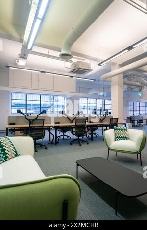 Spacious modern office featuring sleek workstations and cozy lounge areas with stylish furniture Stock Photo