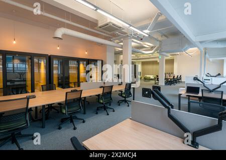 Spacious modern office featuring an open floor plan with well-spaced desks, ergonomic chairs, and private meeting pods Stock Photo