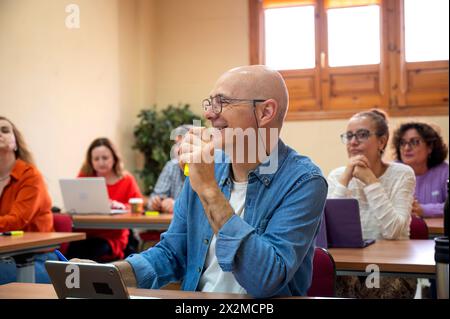Smiling senior man enjoying a learning session with peers in a classroom environment, showcasing the joy of continued education Stock Photo