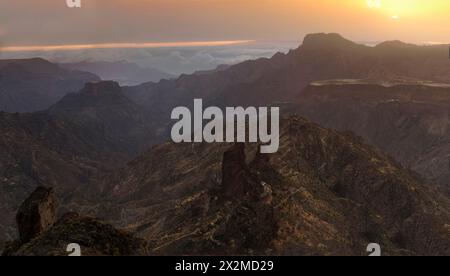 Majestic view of the Roque Bentayga at sunset with soft light casting over the rugged mountains and clouds in the distance on Gran Canaria. Stock Photo