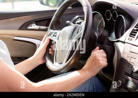 Close-up view of the hands of a person using the steering wheel and gear shift in a car Stock Photo
