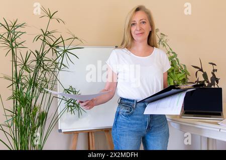 Confident business woman standing in the office, holding some important documents for work Stock Photo