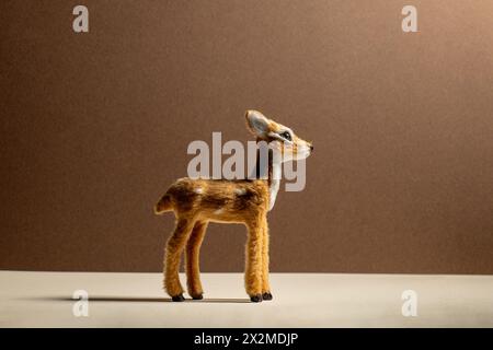 Handcrafted felted wool deer in a studio setting with a brown background. Stock Photo