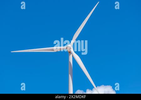 A single wind turbine stands tall against a vibrant blue sky, highlighting sustainable energy Stock Photo