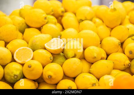 A vibrant heap of fresh, ripe lemons with a single lemon cut in half, showcasing its juicy interior Stock Photo