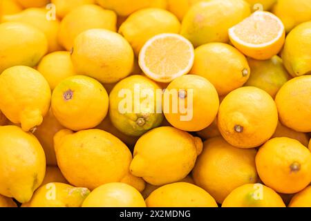 A vibrant, close-up image of fresh, ripe lemons with one cut lemon slice revealing juicy interior Stock Photo