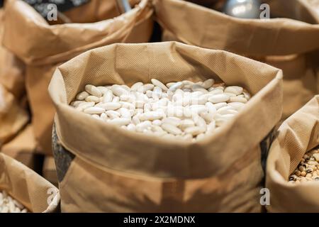 Close-up image of bulk white beans in a burlap sack with other grains in the background at an organic market Stock Photo