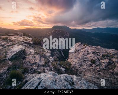 Serene sunset over the breathtaking ridges of Rio Mundo, with dramatic clouds and the vibrant sky casting a warm glow over the rugged landscape Stock Photo