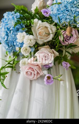 Elegant bridal bouquet featuring hydrangeas, roses, and lisianthus on a white dress backdrop Stock Photo
